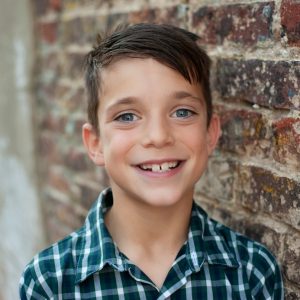 boy in blue and white plaid button up shirt smiling