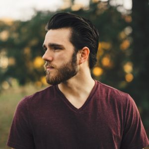 man wearing maroon V-neck t-shirt in forest