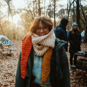 a woman wearing a scarf standing in the woods