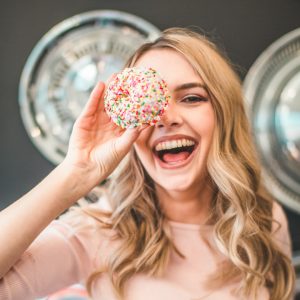 shallow focus photography of woman holding doughnut